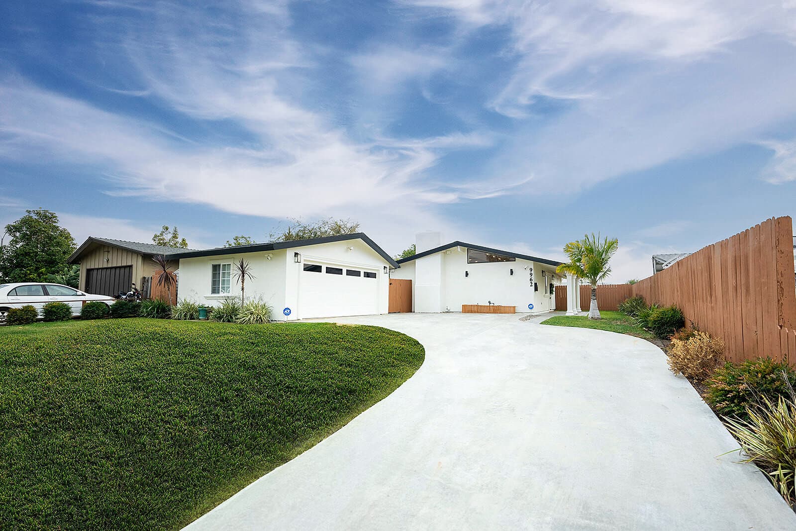 Repainted white house exterior with new curved driveway and landscaping